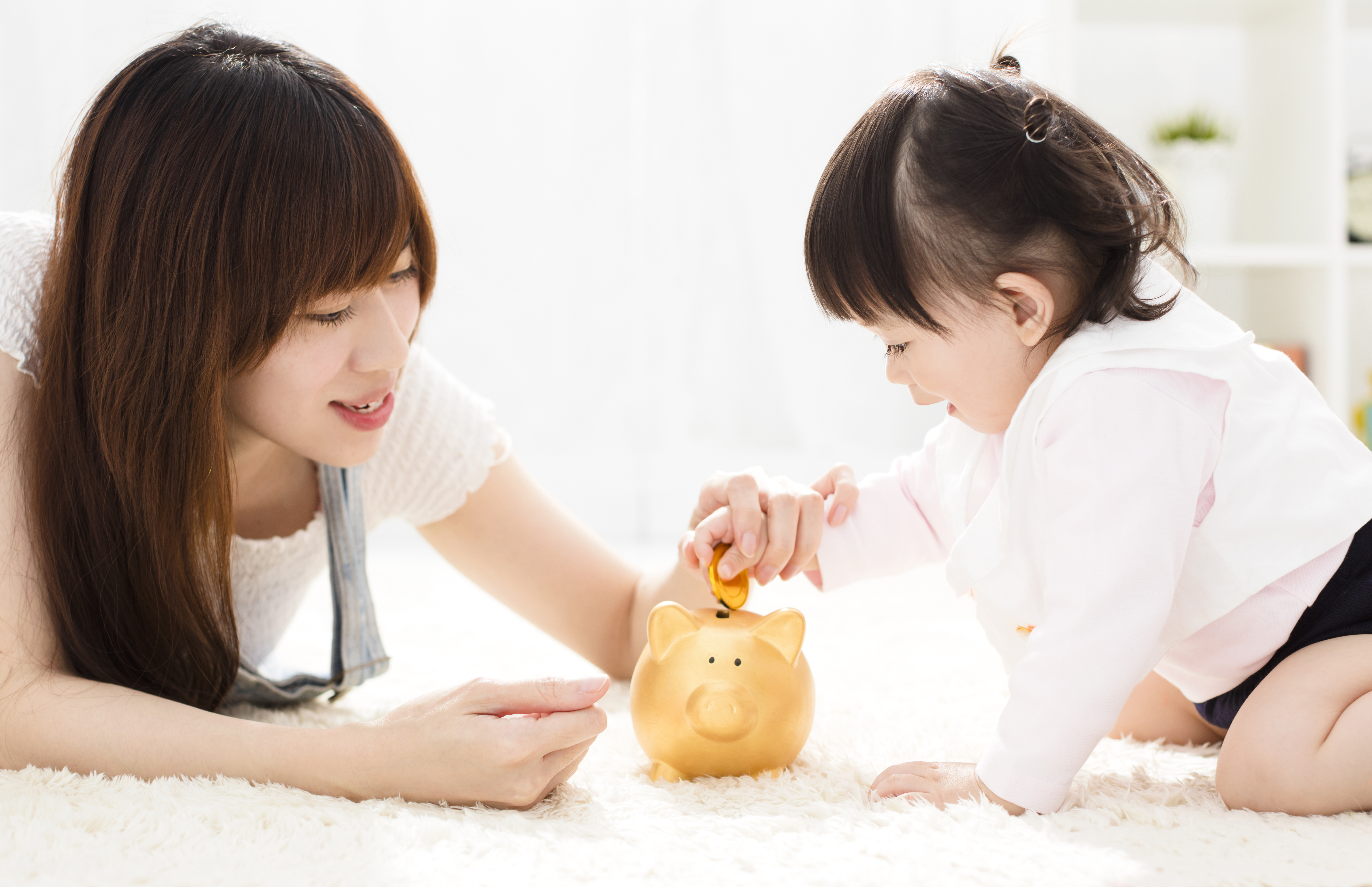 Mother and daughter putting coins into piggy bank